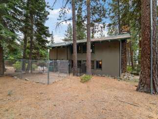 Discover this charming property nestled among tall pine trees, offering a private fenced yard perfect for pets or outdoor activities.