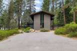 Nestled amidst tall pine trees, this modern home offers a unique architectural design with a striking facade and expansive windows.