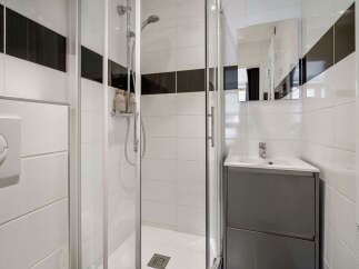This modern bathroom features a sleek glass-enclosed shower and a stylish vanity with a built-in sink.