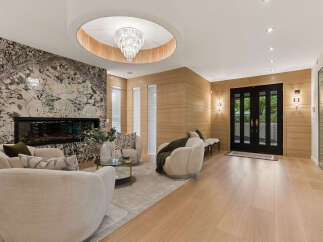 Experience luxury living in this stunning modern living room, featuring a dramatic marble fireplace and a captivating crystal chandelier.