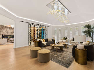 Experience luxury living in this stunning modern living room, featuring a sleek wine rack, elegant chandelier, and comfortable seating arrangements.