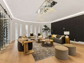 Experience luxury living in this stunning living room, featuring a modern crystal chandelier and a sleek wine cellar.