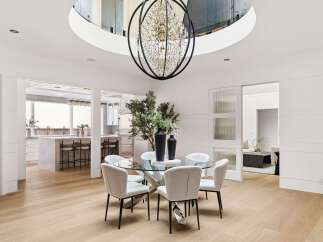 Experience modern luxury in this stunning dining area, featuring a sleek glass-top table surrounded by elegant upholstered chairs.