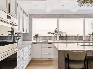 Experience luxury in this modern kitchen featuring sleek white cabinetry with elegant gold hardware.