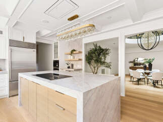 Experience luxury in this stunning modern kitchen, featuring a sleek marble island with an integrated cooktop and a professional-grade stainless steel refrigerator.