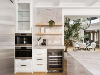 Experience modern luxury with this sleek kitchen featuring integrated Wolf appliances, including a coffee maker and oven.