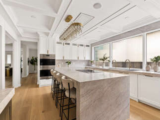 Experience luxury in this stunning modern kitchen, featuring a grand marble island with bar seating and a sleek induction cooktop.