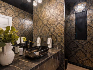 Experience luxury in this stunning powder room, featuring opulent damask wallpaper in gold and black.