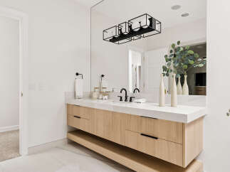 Experience modern luxury in this stunning bathroom featuring a sleek, floating vanity with natural wood cabinetry and a pristine white countertop.
