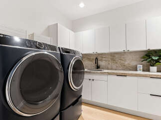 This modern laundry room features a sleek GE Profile washer and dryer set in a sophisticated dark finish.