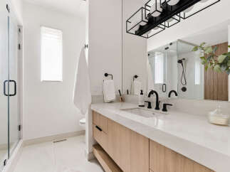Experience modern luxury in this stunning bathroom, featuring a sleek vanity with natural wood cabinetry and a pristine white quartz countertop.