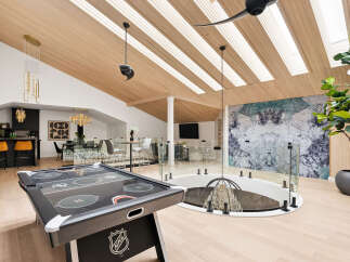 Experience luxury and entertainment in this stunning multi-level living space, featuring a modern air hockey table and a sophisticated dining area.