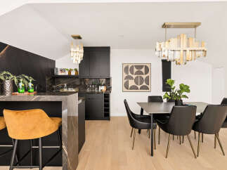 Experience modern luxury in this stunning dining and kitchen area, featuring a sleek dark cabinetry and a dramatic marble-clad island.
