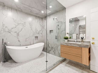 Experience modern luxury in this stunning bathroom, featuring a freestanding soaking tub and a spacious glass-enclosed shower with a rainfall showerhead.