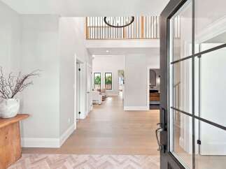 Step into a grand foyer with soaring ceilings and a modern chandelier, setting the tone for this luxurious home.