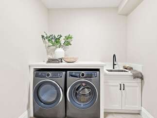 This modern laundry room features a sleek Electrolux washer and dryer set, complemented by a stylish undermount sink and black faucet.