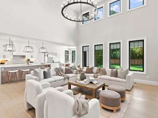 Experience luxury living in this stunning open-concept home, featuring a soaring double-height living room with a grand chandelier and expansive windows.