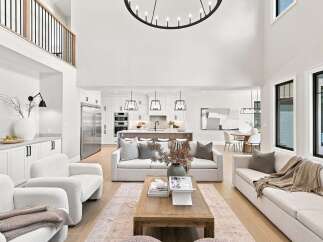 Experience modern luxury in this open-concept living space, featuring a soaring ceiling and a sleek chandelier.