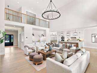 Experience modern luxury in this stunning open-concept living space, featuring a soaring ceiling and a grand circular chandelier.
