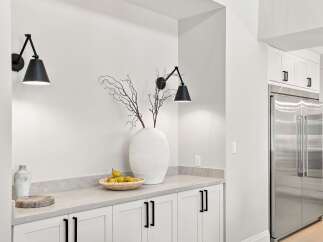 This modern kitchen features sleek white cabinetry with black hardware, complemented by a stainless steel refrigerator.