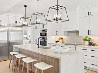 Experience luxury in this modern kitchen featuring sleek white cabinetry, a large stainless steel refrigerator, and a stunning waterfall island with a built-in sink and black faucet.