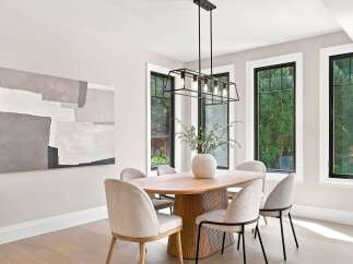 Experience elegant dining in this beautifully appointed space, featuring a stunning abstract art piece and a modern chandelier.