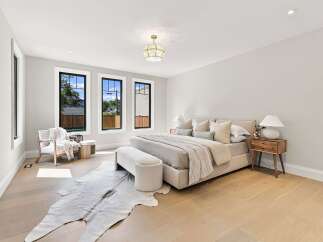 Experience luxury and comfort in this beautifully appointed bedroom, featuring a plush king-sized bed adorned with elegant pillows and a cozy knit throw.