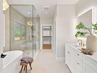 Experience luxury in this stunning modern bathroom, featuring a freestanding soaking tub and a spacious glass-enclosed shower with elegant gold fixtures.