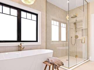 Experience luxury in this stunning bathroom, featuring a freestanding soaking tub and a spacious glass-enclosed shower with elegant gold fixtures.