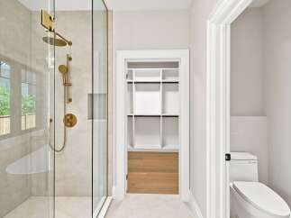 Experience modern luxury in this bathroom featuring a sleek glass-enclosed shower with elegant gold fixtures.