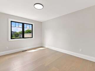 Experience modern living in this bright and airy room, featuring a large window with a black frame that floods the space with natural light.
