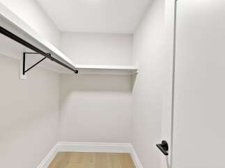 Discover ample storage in this spacious walk-in closet, featuring a sleek black hanging rod and a clean white shelf.