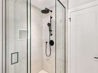 Experience luxury in this modern bathroom featuring a sleek glass-enclosed shower with a rainfall showerhead and handheld wand.
