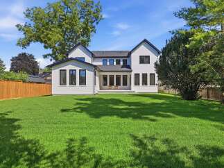 Discover this stunning modern home featuring a crisp white exterior with dark trim and a spacious, manicured lawn perfect for outdoor enjoyment.