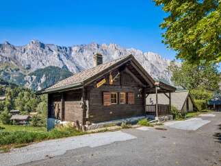 Experience rustic charm in this traditional wooden chalet nestled against a breathtaking mountain backdrop.
