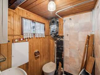 This rustic bathroom features charming wooden paneling and a functional toilet and sink area.