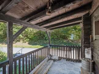 Step onto the charming wooden porch of this rustic property, offering a perfect spot to enjoy the surrounding natural beauty.