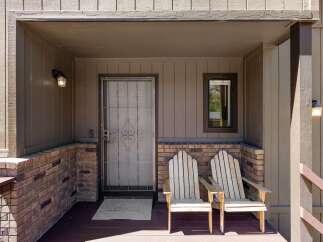 Welcome guests to your home with this charming front porch, featuring two Adirondack chairs perfect for relaxing.