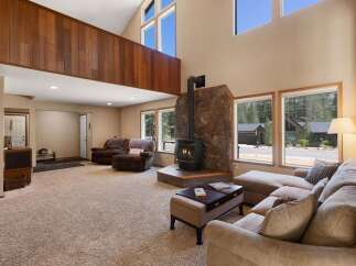 Experience cozy living in this spacious living room featuring a striking stone fireplace with a wood-burning stove, perfect for chilly evenings.