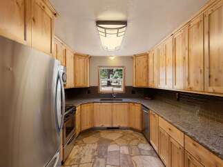 Discover this charming kitchen featuring warm, natural wood cabinetry that complements the granite countertops and a stylish subway tile backsplash.