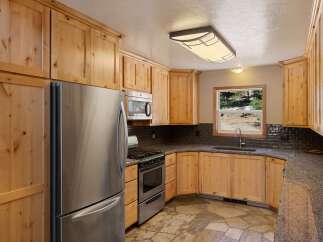 This charming kitchen features light wood cabinetry and a stainless steel refrigerator, offering ample storage and a clean, modern aesthetic.