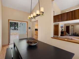 Experience comfortable living in this spacious dining area, featuring a large dark wood table perfect for gatherings and a sliding glass door that opens to the outdoors.