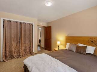 This cozy bedroom features a comfortable bed with decorative pillows and a unique wooden headboard adorned with a dandelion motif.