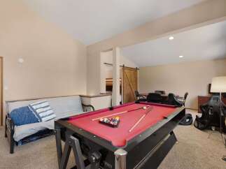 This versatile game room features a vibrant red pool table, perfect for friendly competitions.