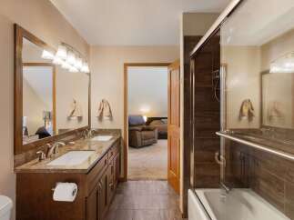 This spacious bathroom features a double vanity with granite countertops and ample storage, perfect for any household.