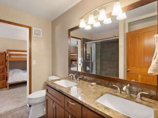 This spacious bathroom features a double vanity with granite countertops and modern fixtures, perfect for busy mornings.