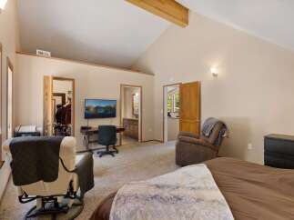 This spacious bedroom features a vaulted ceiling with exposed beams, creating an airy and open atmosphere.