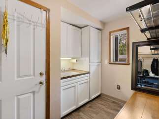 This laundry room offers ample storage with white cabinets and a convenient sink area.