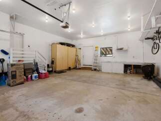 Discover ample storage and workspace in this spacious garage, featuring tall cabinets and a convenient workbench area.