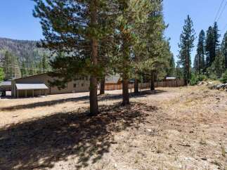 Discover this expansive property featuring a large, versatile building ideal for commercial or residential use, nestled amidst a backdrop of majestic mountains and lush pine trees.